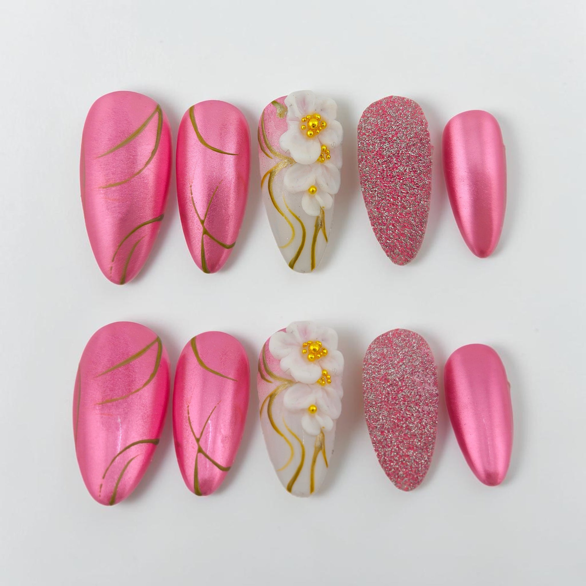 Auntie Cookies Nails pink chrome almond press-on nails with gold lines and 3D floral accent.