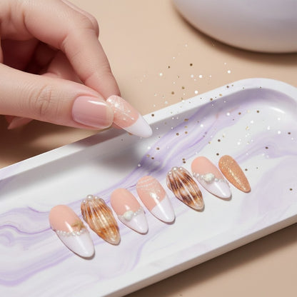 Auntie Cookies Nails: Set of press-on nails with seashell, pearl, and lace designs in white, peach, and gold.