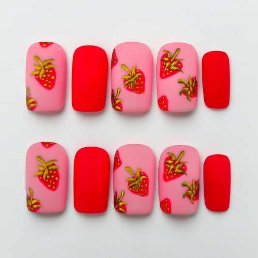 Auntie Cookies Nails matte pink and red press-on nails with gold and red strawberry designs.