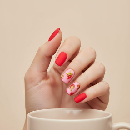 Auntie Cookies Nails strawberry press-on nails with pink background and red strawberry designs, plus solid matte red nails.