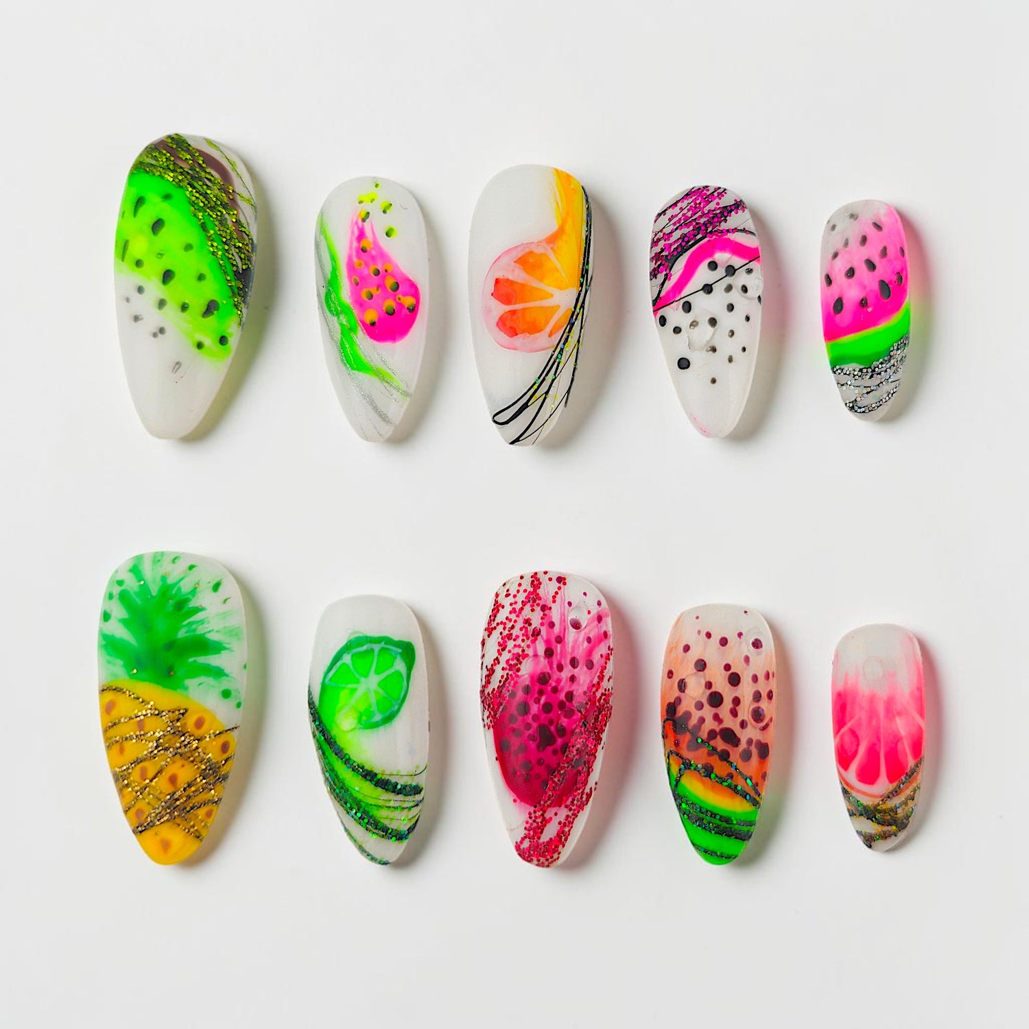 Auntie Cookies Nails: Assorted fruit-themed press-on nails with watermelon, pineapple, lime, and orange designs, featuring glitter and vibrant colors.